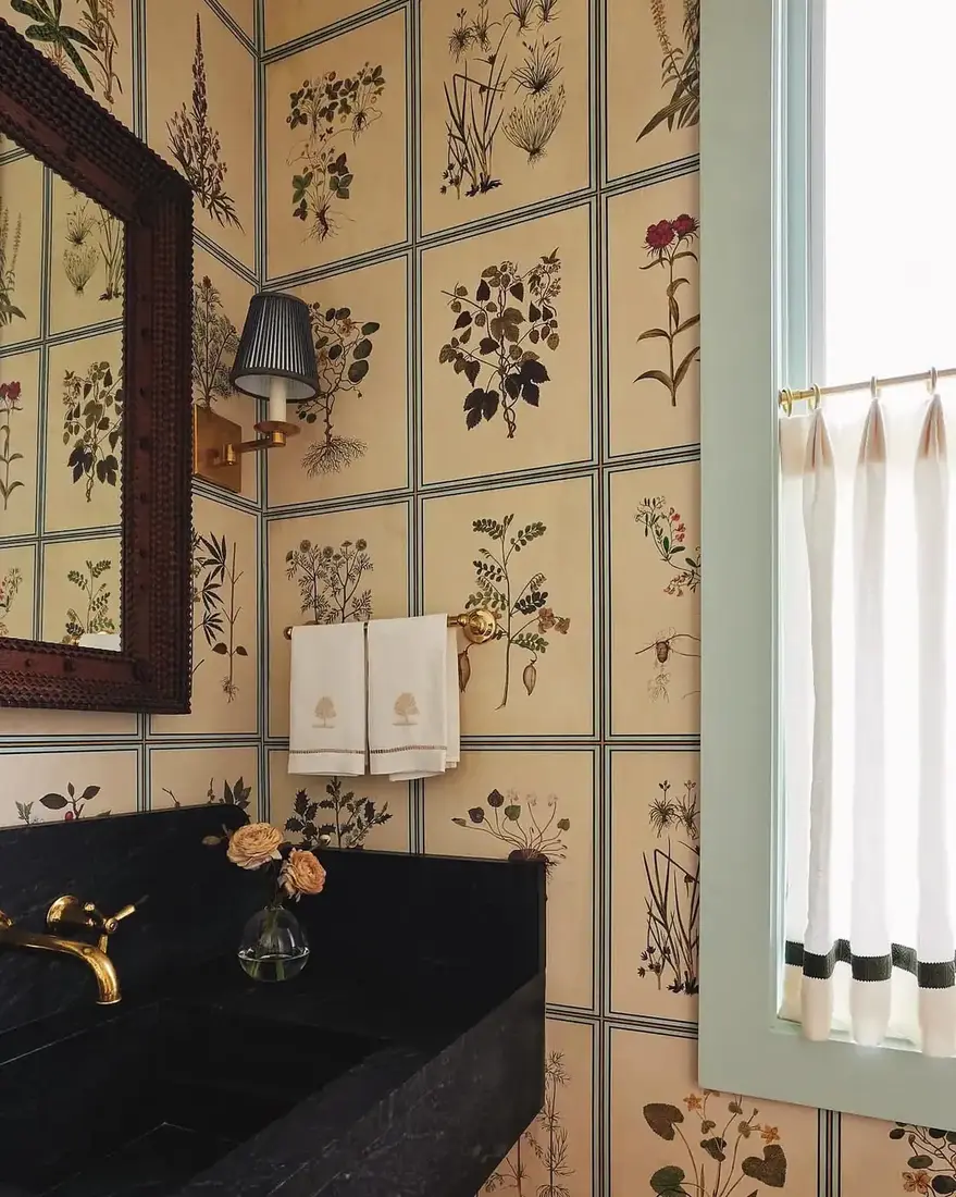 Powder room with gridded botanical wallpaper, black stone vanity and brass tap