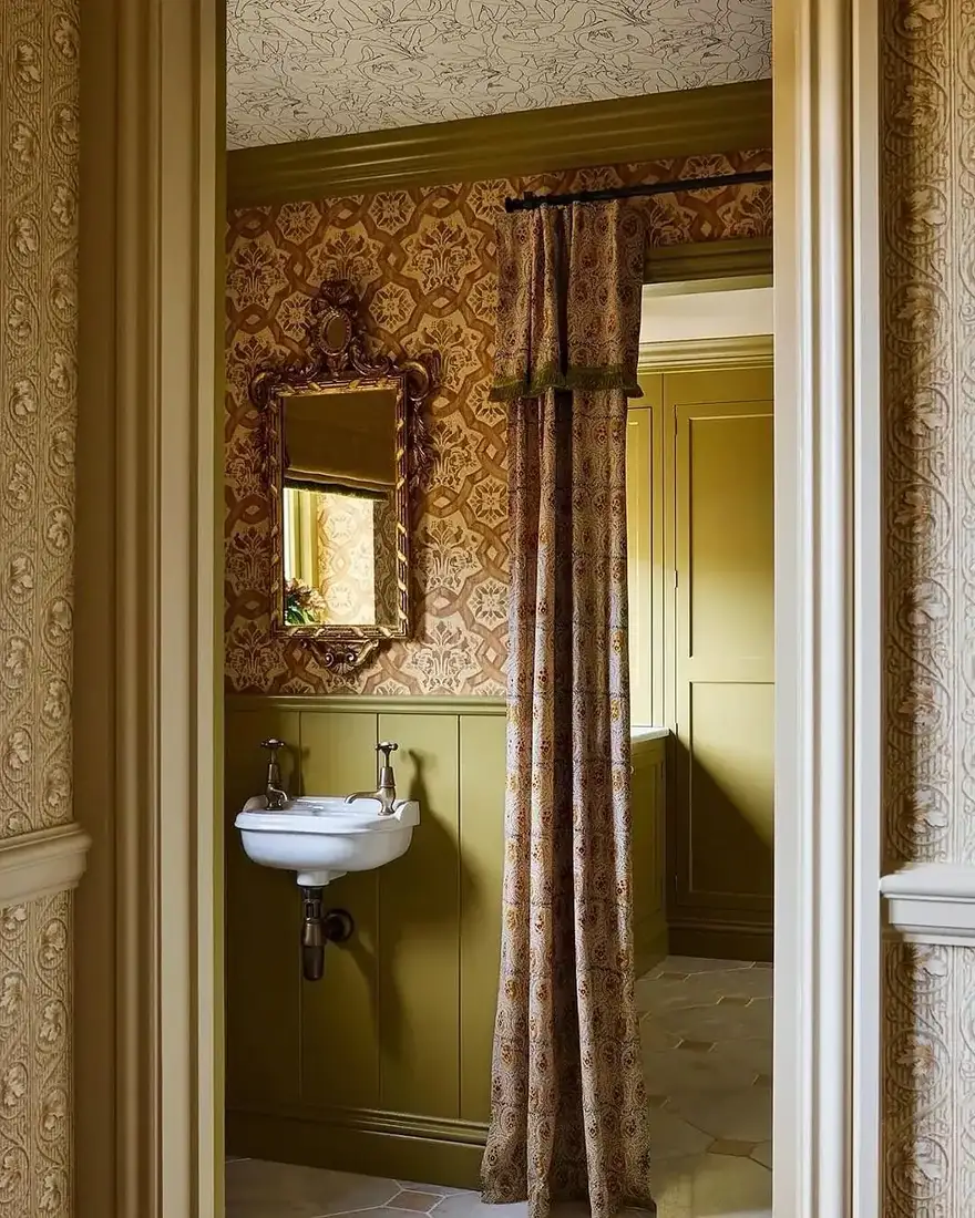 Olive panelled powder room with damask wallpaper, wall-hung basin and patterned curtain