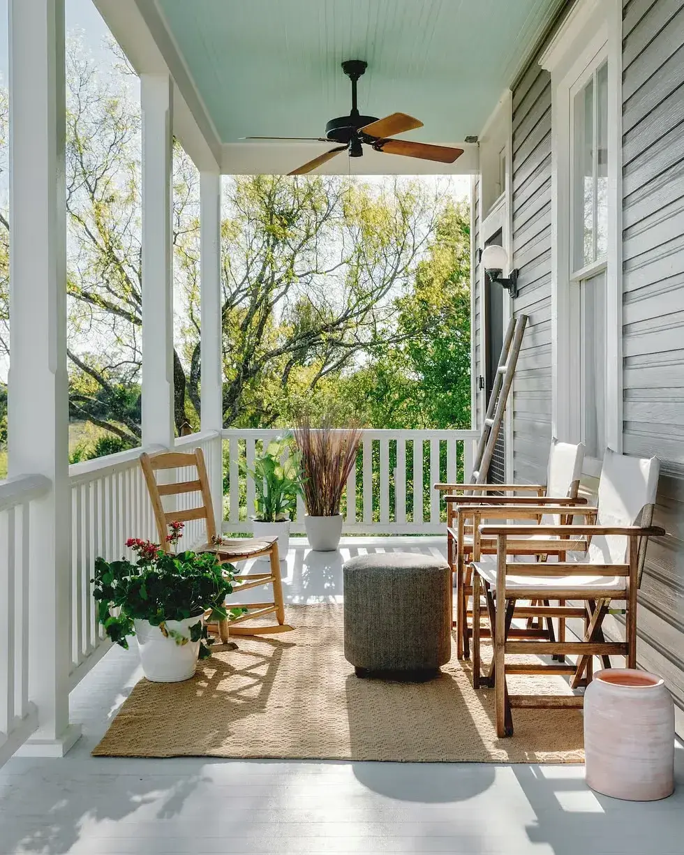 Covered porch with rocking chairs and a pale blue ceiling over a jute rug