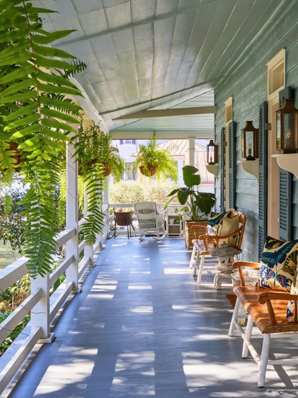 Long shaded porch with a blue grey painted floor and hanging ferns