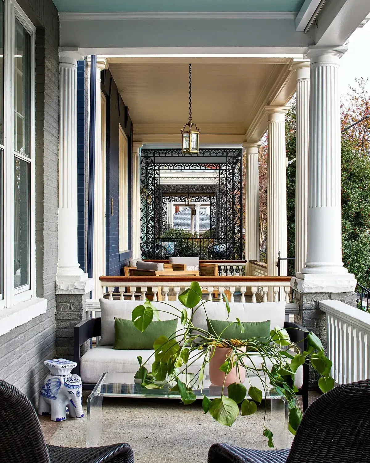 Shaded porch with a deep blue wall, white columns, and a pale sofa