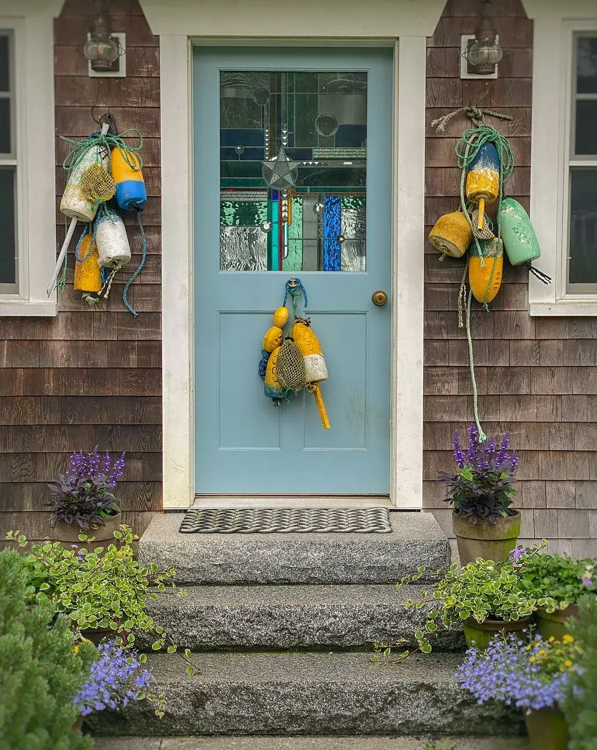 Pale sky blue door with stained glass on dark shingle with buoys