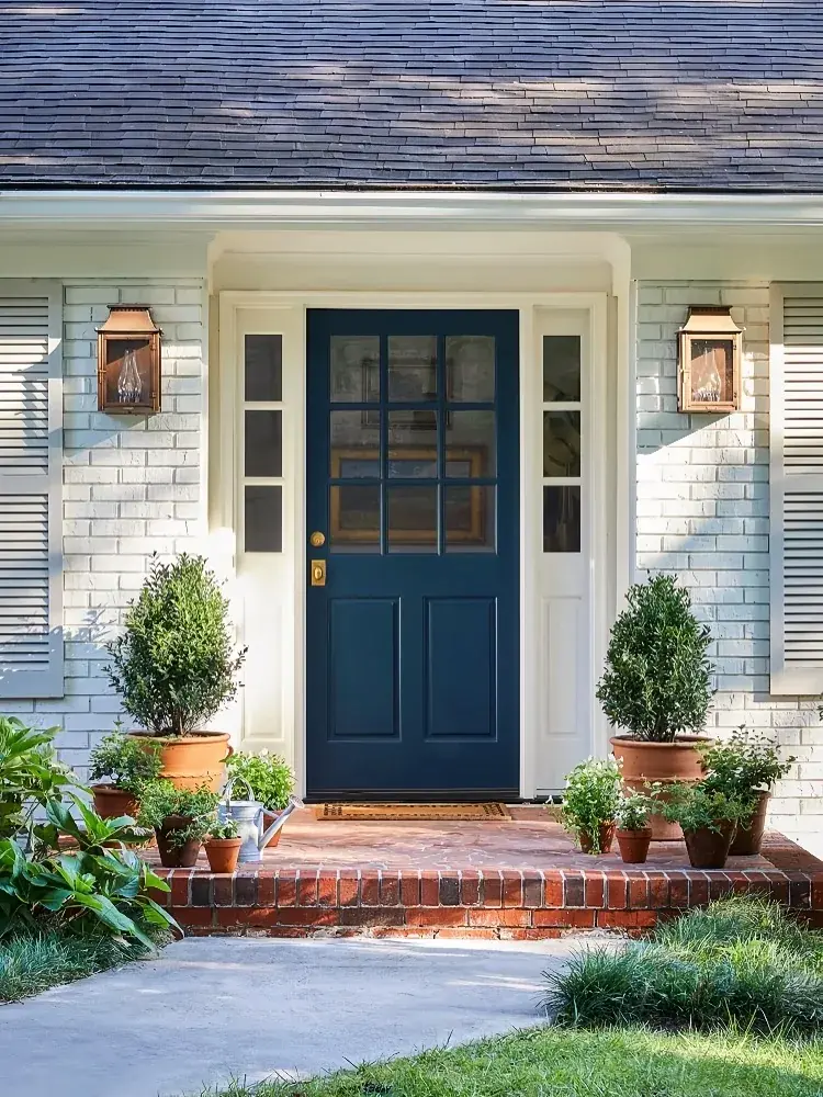 Navy glazed door on white painted brick with copper lanterns and topiaries