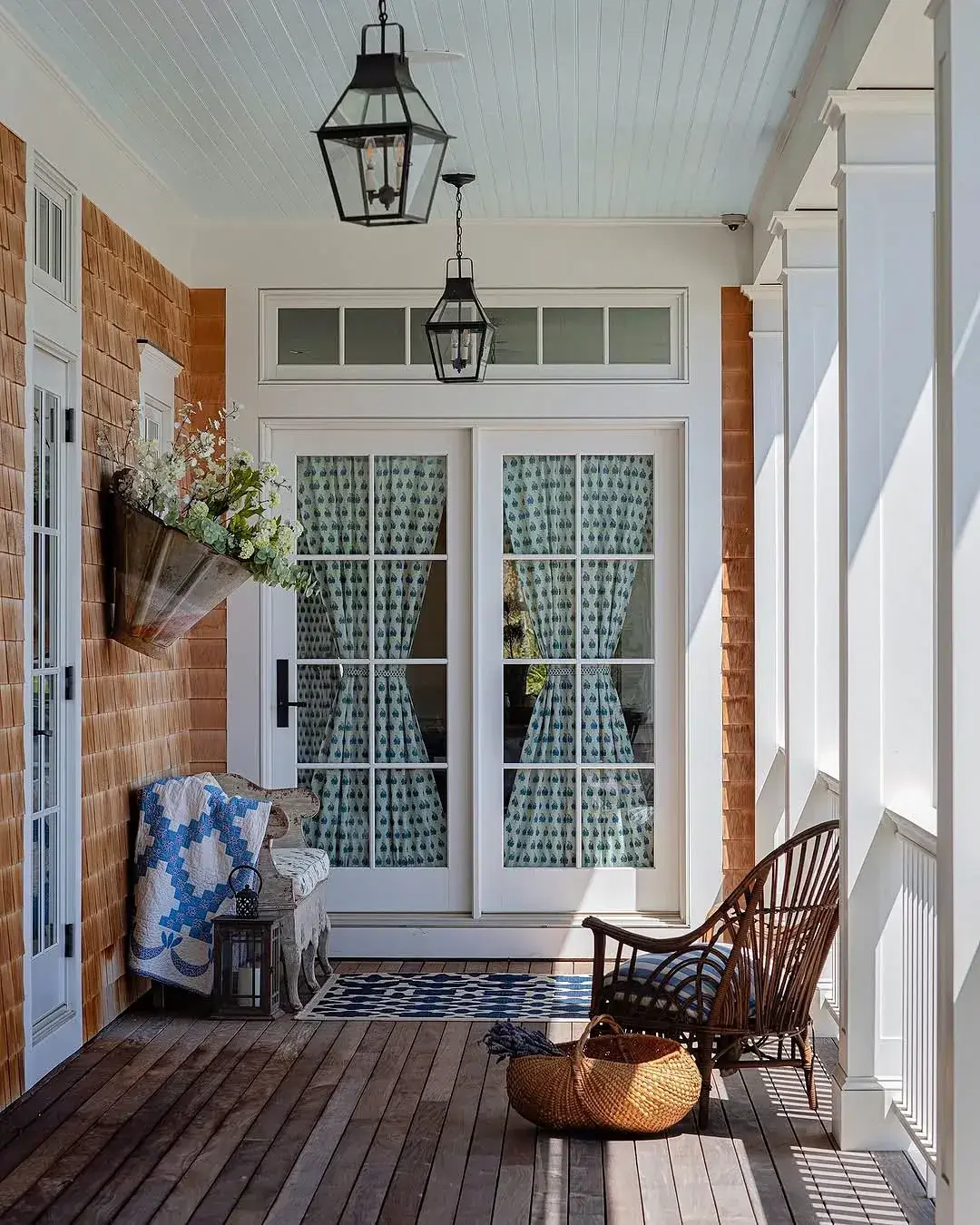 Timber boarded porch with French doors, wicker chair and hanging lanterns