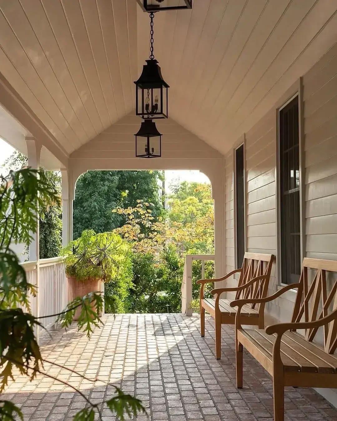 Covered porch with a brick paver floor, vaulted boarded ceiling and hanging lanterns