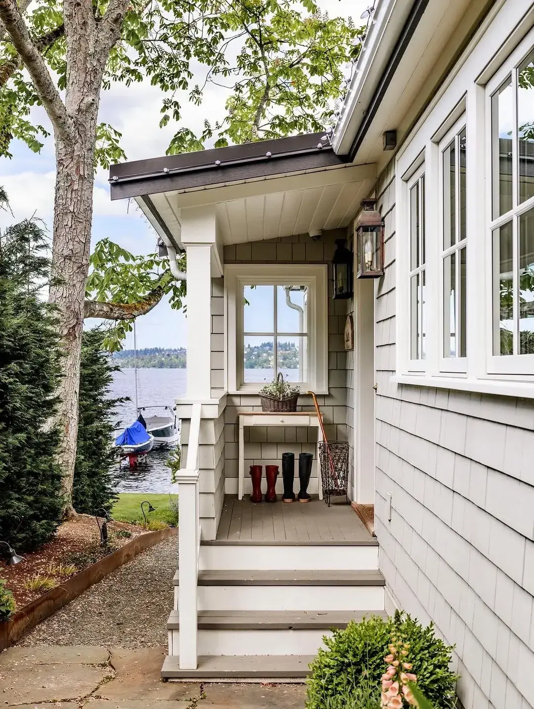 Shingle side porch with painted timber steps, wellington boots and lake beyond