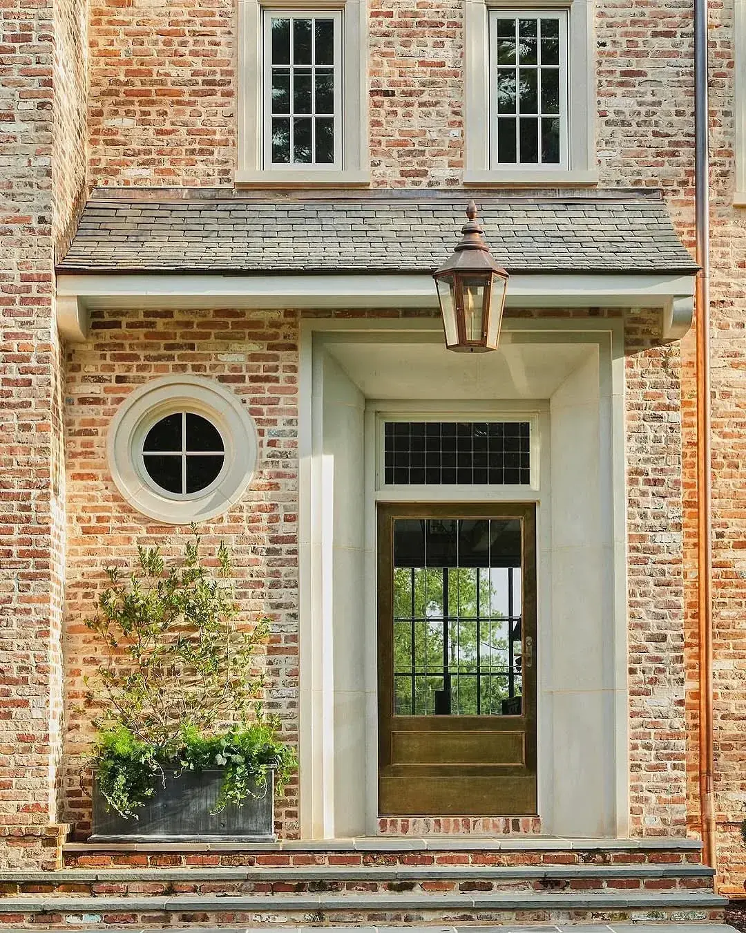 Brick entry with glass panelled door, stone treads and copper lantern