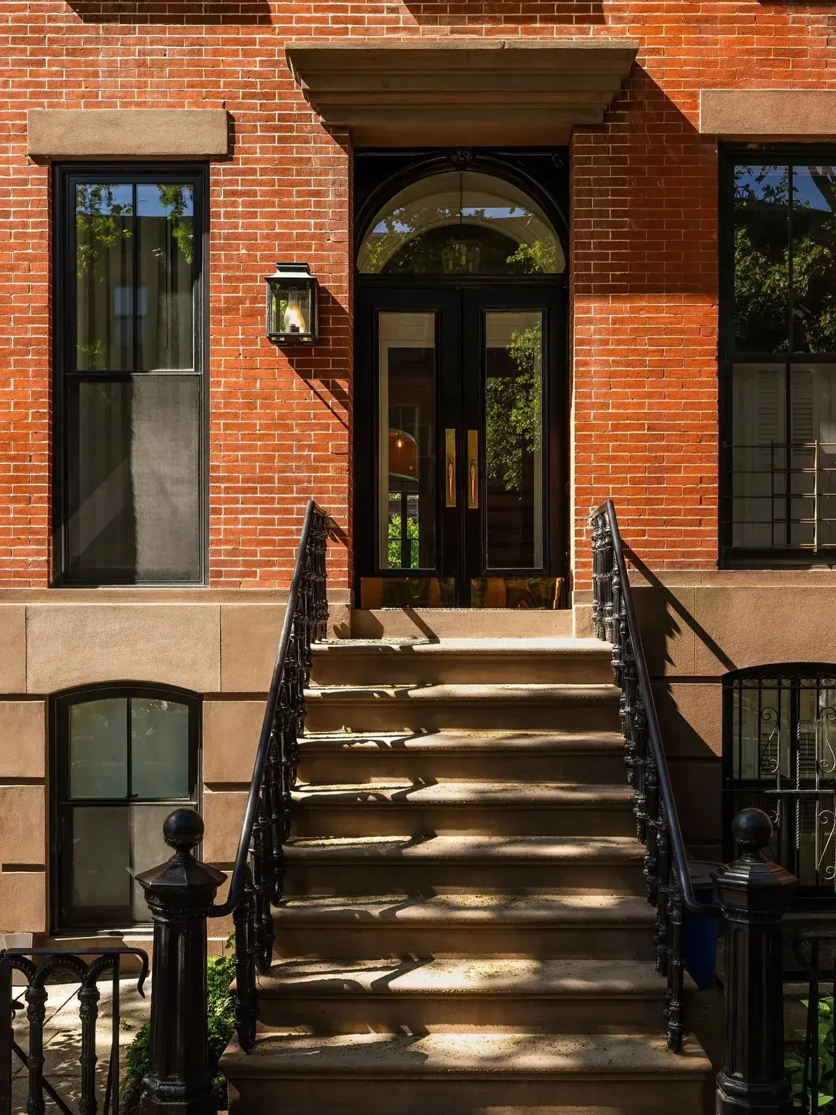 Red brick townhouse with stone stoop steps and black iron railings