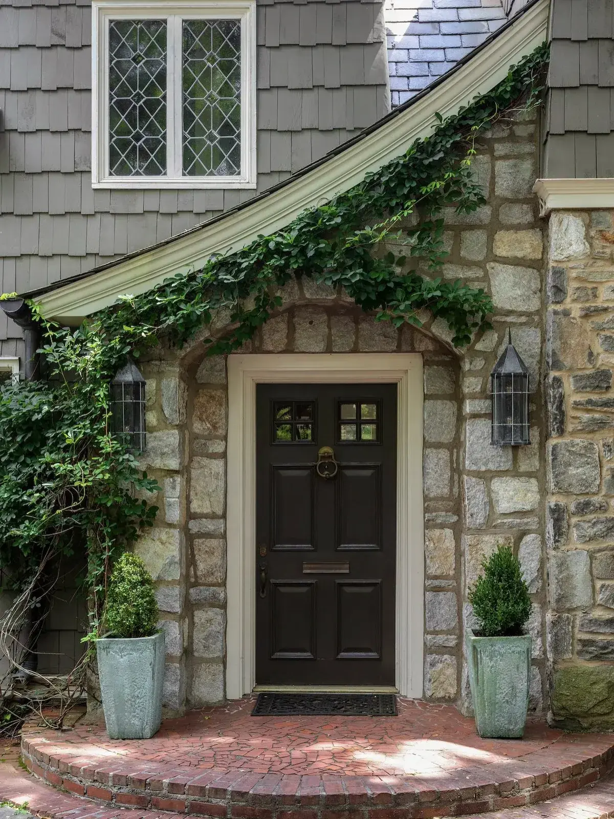 Stone cottage with curved brick porch platform and dark panelled door
