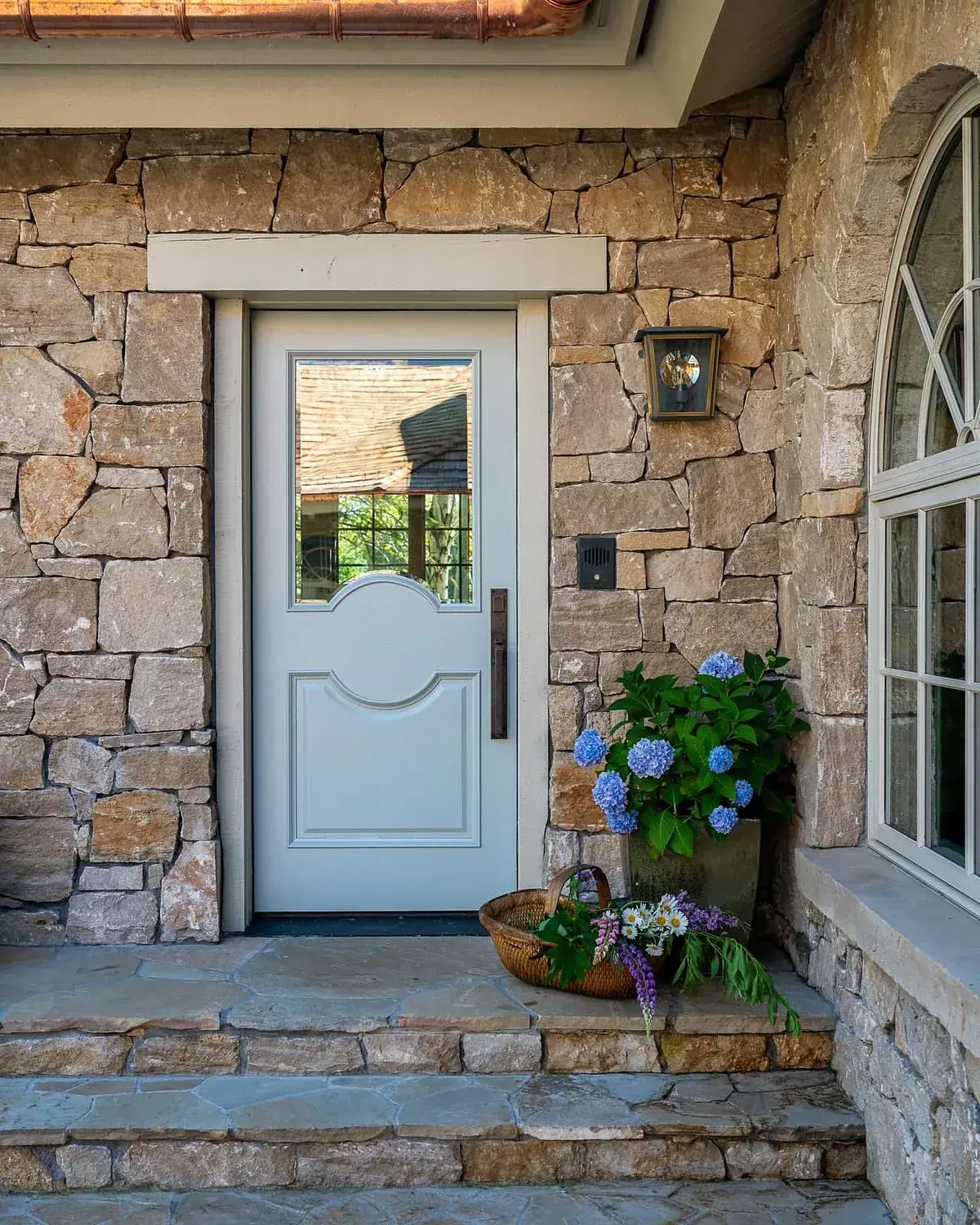 Stone house with pale door, stone steps and hydrangeas