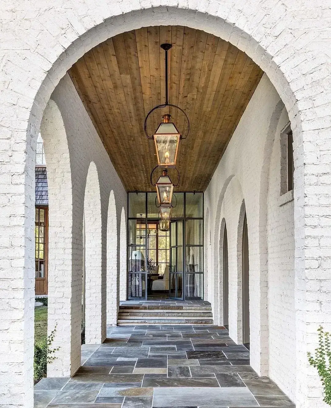 White painted brick arcade with slate floor and hanging lanterns