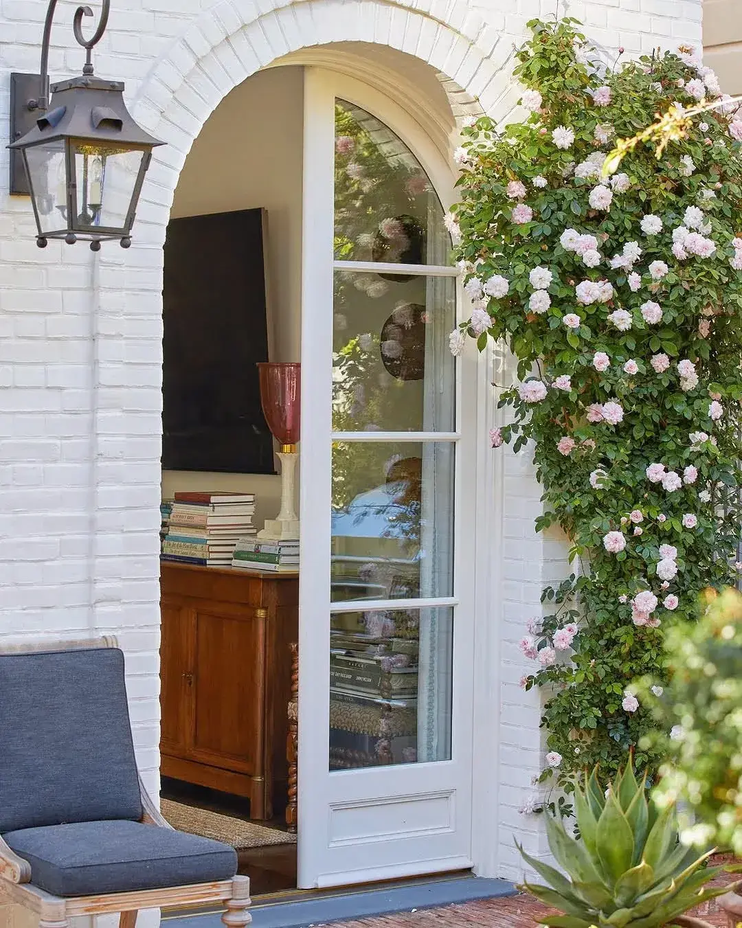 White brick arch with climbing roses, glazed door and lantern