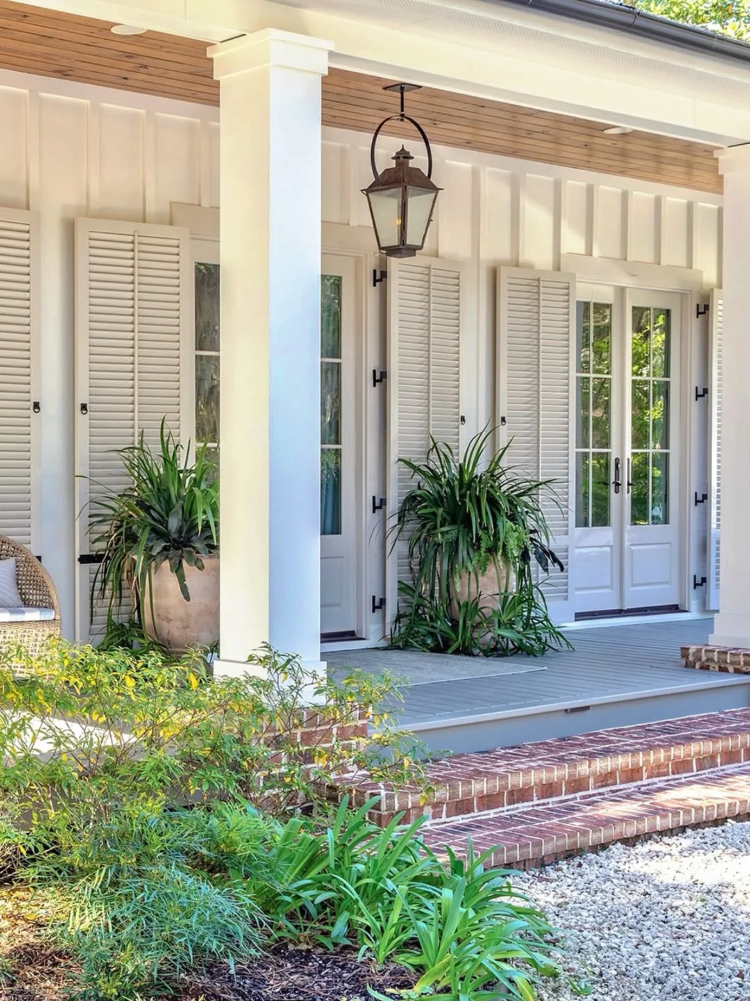 Pale porch with a timber boarded ceiling, a large hanging lantern, tall potted plants and grey painted deck