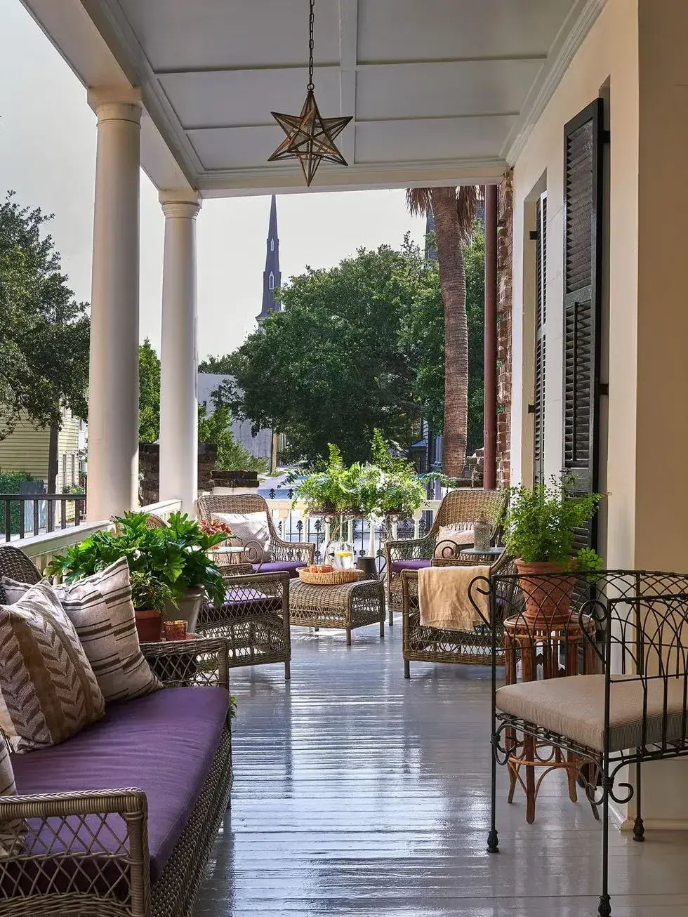 Deep veranda with round columns, wicker seats and a hanging star lantern