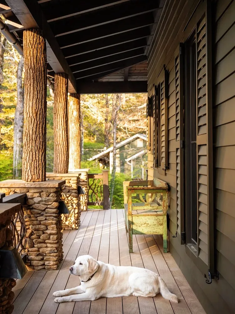 Rustic porch with bark covered log posts on river stone piers