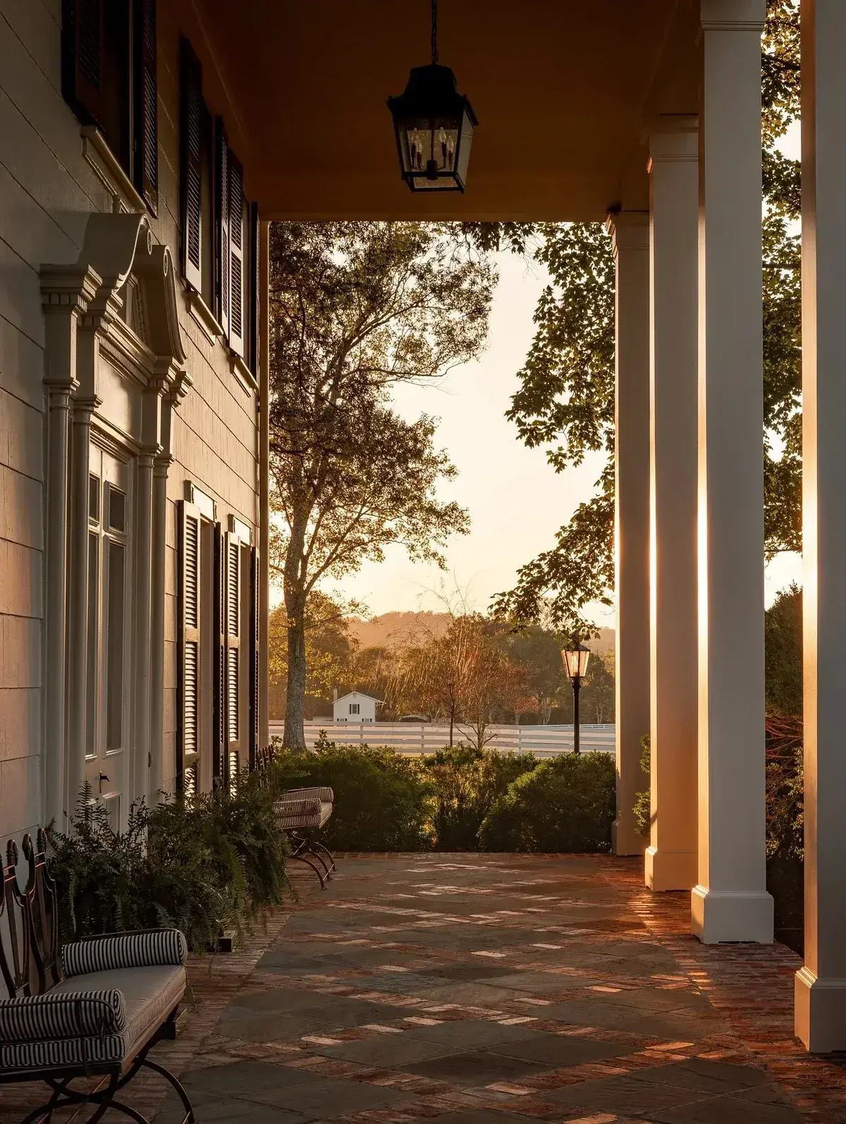 Long side porch at sunset with tall square columns and a patterned floor