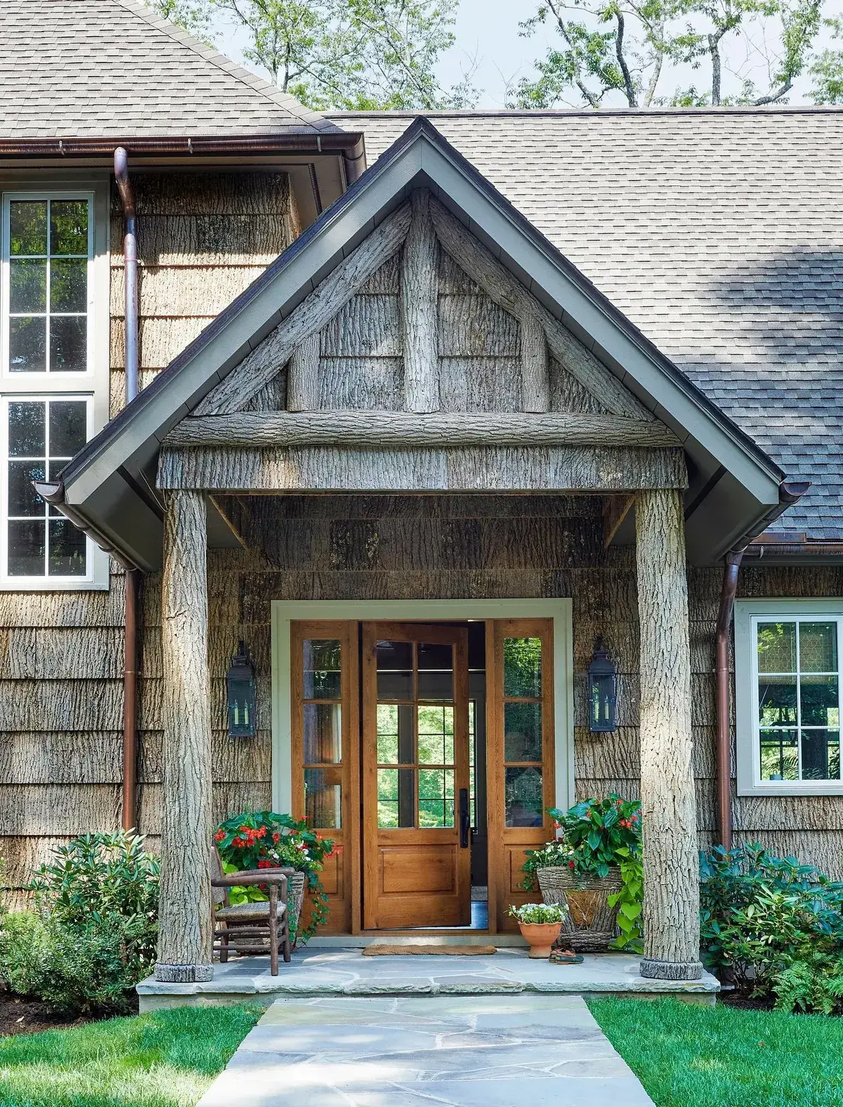 Bark clad gable portico on two tree trunk columns over a stone entry