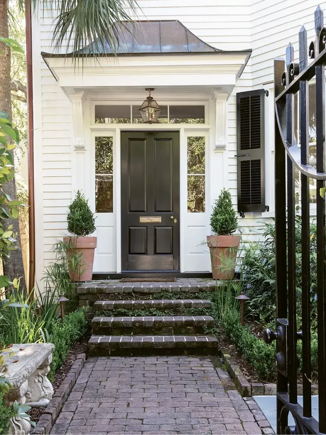 Black panelled door under a small bracketed canopy with brick steps