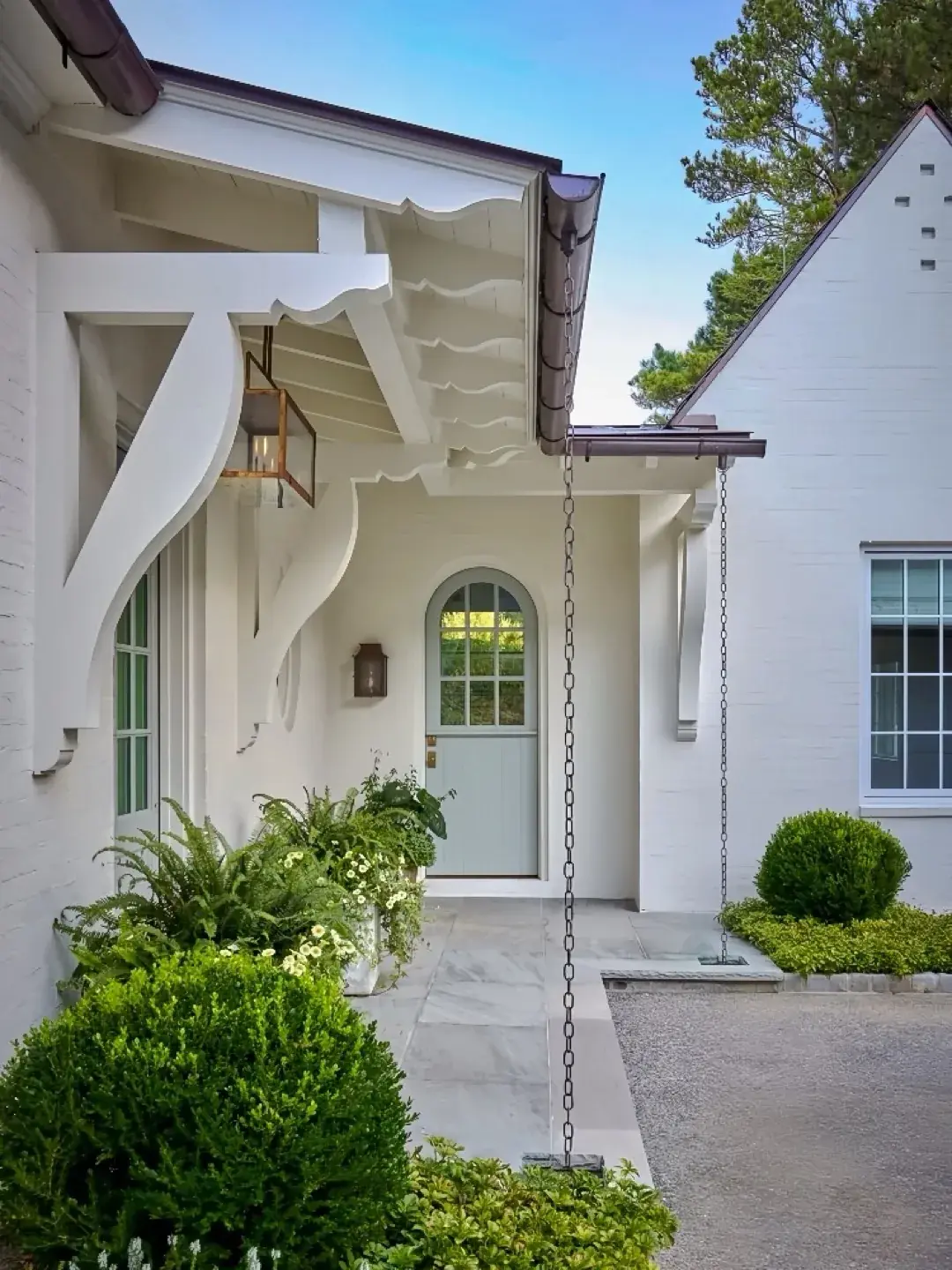Pale mint Dutch door with arched glazing in white painted brick entry
