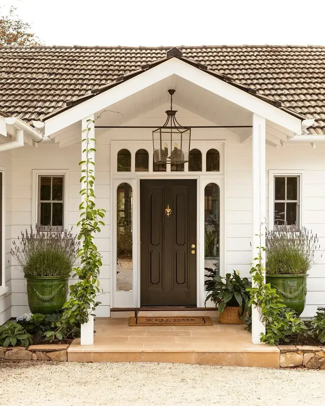 Matched green glazed planters holding clipped lavender either side of a dark front door