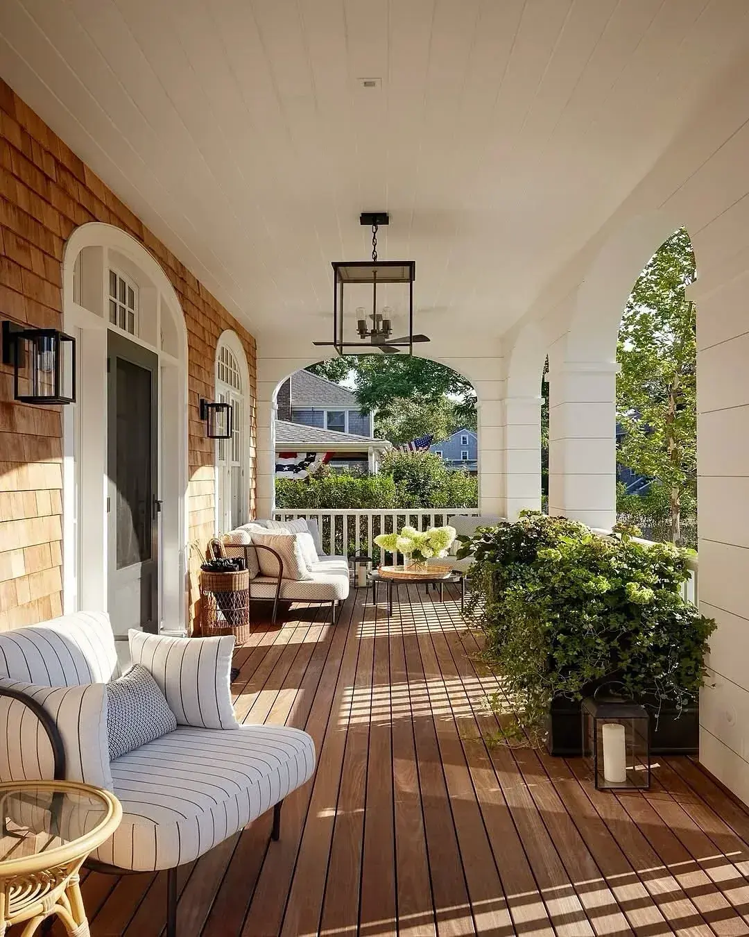 Deep covered porch with arched openings, hardwood decking and two seating groups