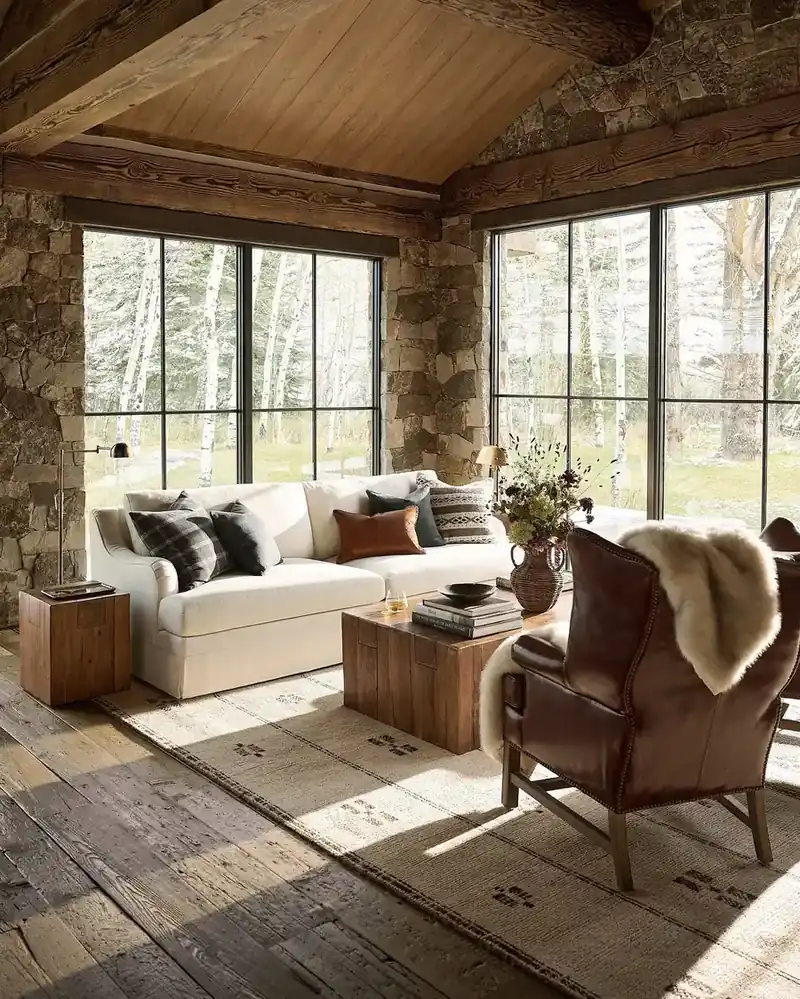 Stone and timber room with a completely plain cream sofa and one leather wing chair