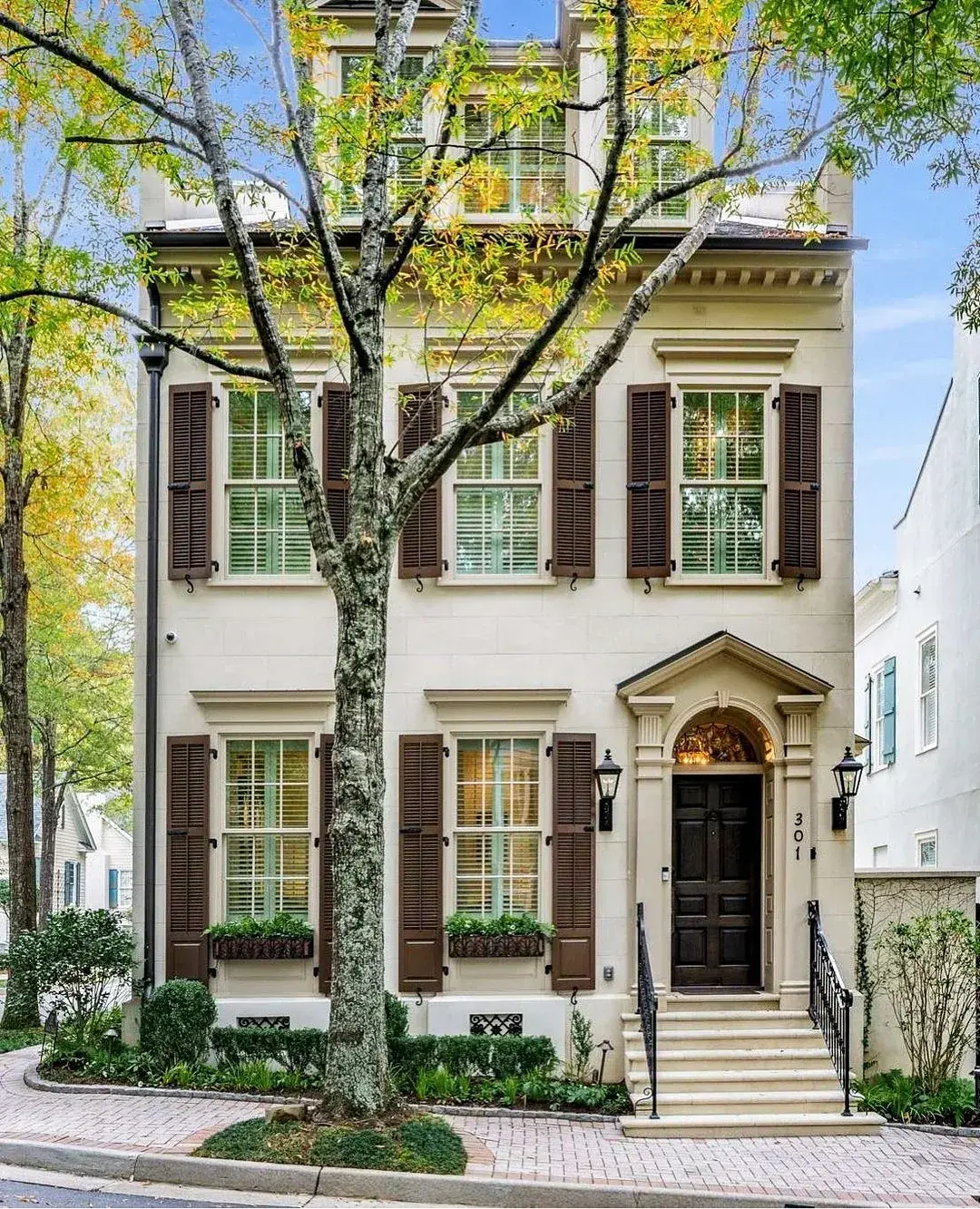 Cream townhouse with dark brown louvered shutters, shutter dogs and matching window boxes