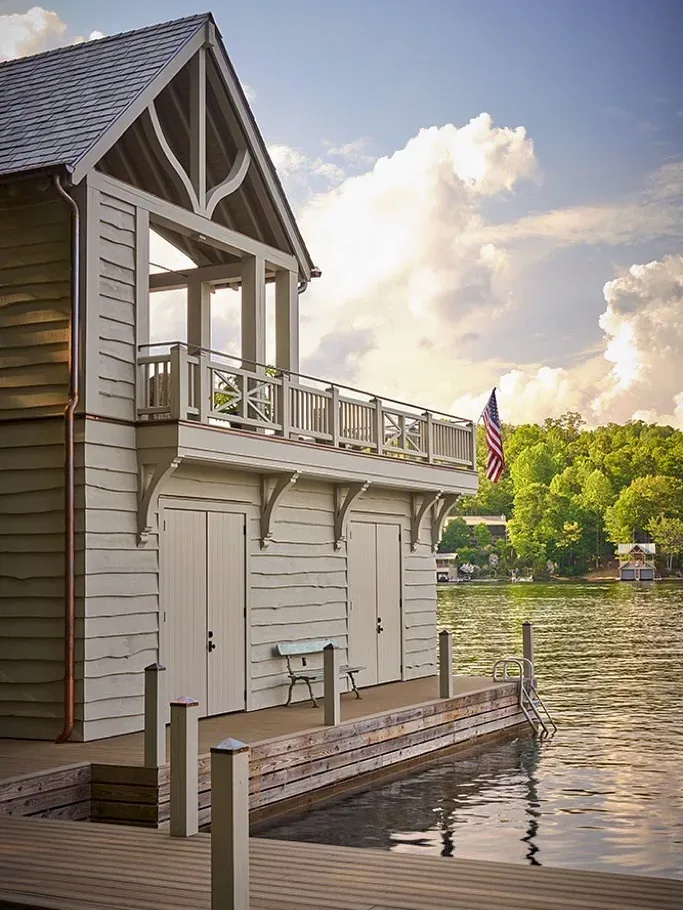 Cream boathouse with horizontal boarding, upper balcony and dock over the water
