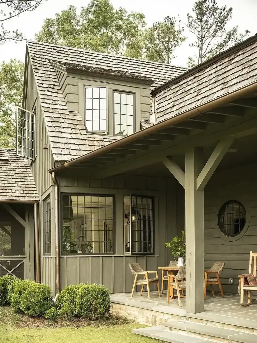 Olive cottage with mixed boarding, deep porch, shingle roof and round window
