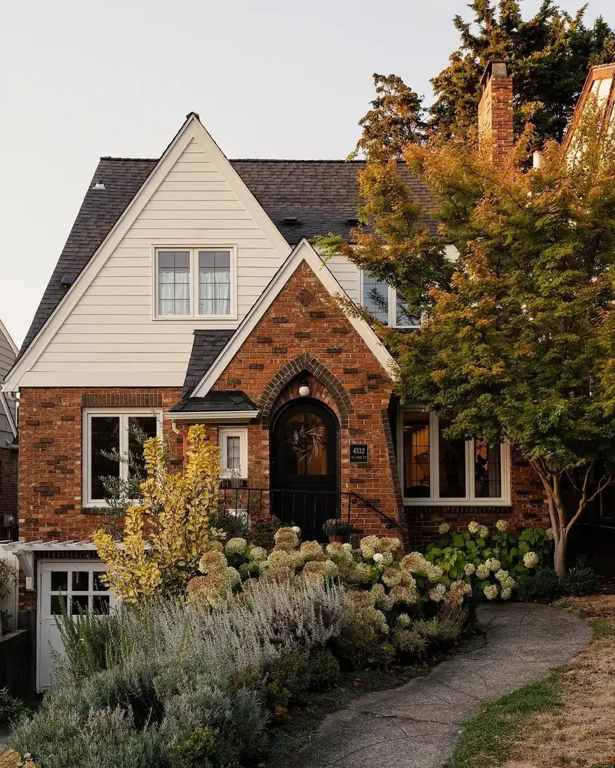 Brick Tudor cottage with an arched front door and planting along the wall