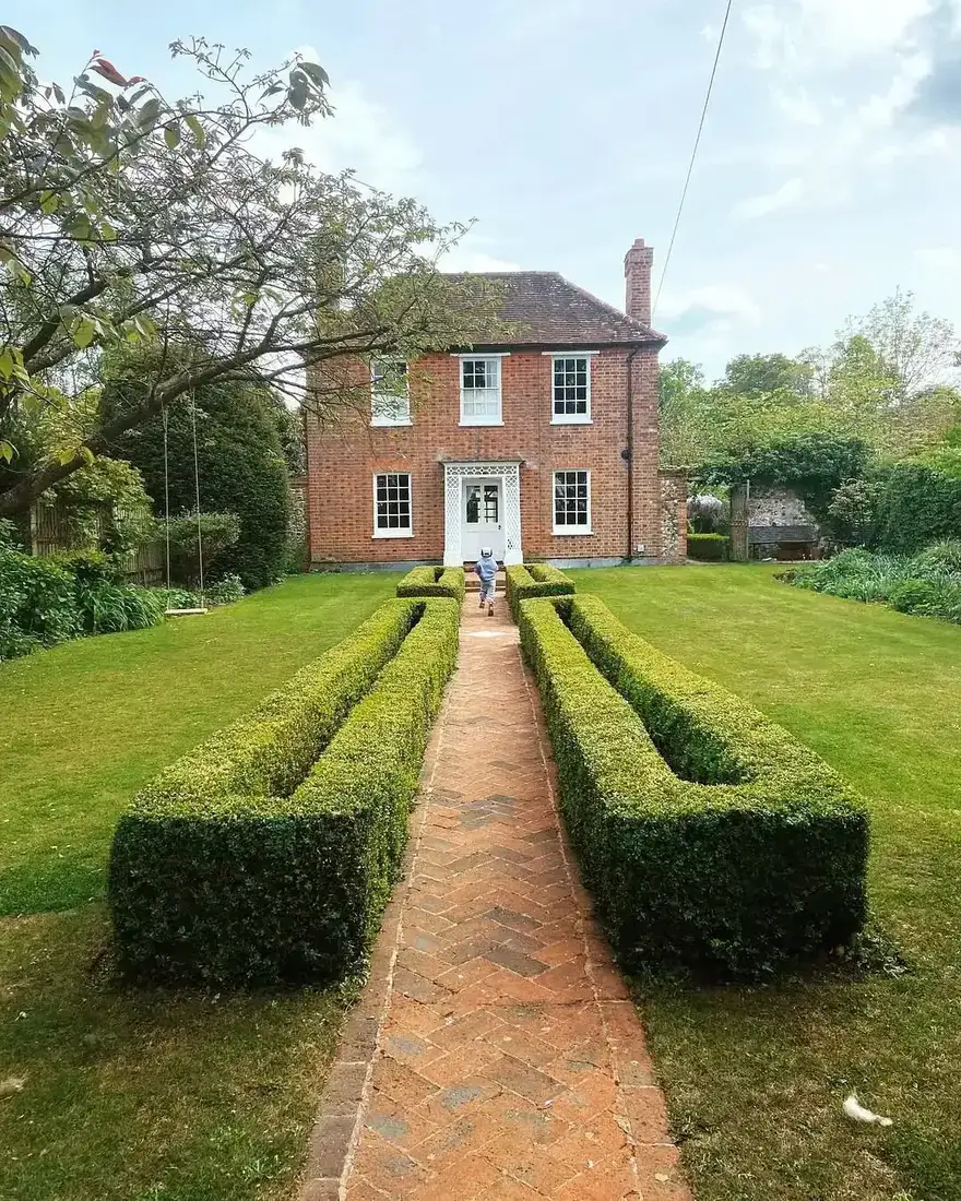 Red brick Georgian farmhouse with white sash windows and a brick herringbone path