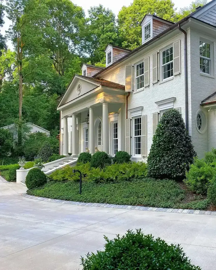 White brick colonial house with a columned porch and shutters painted the same white