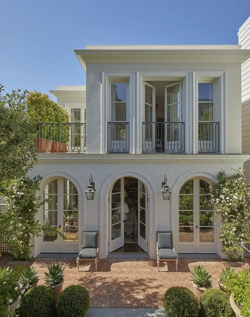 White brick house with arched French doors and a brick terrace