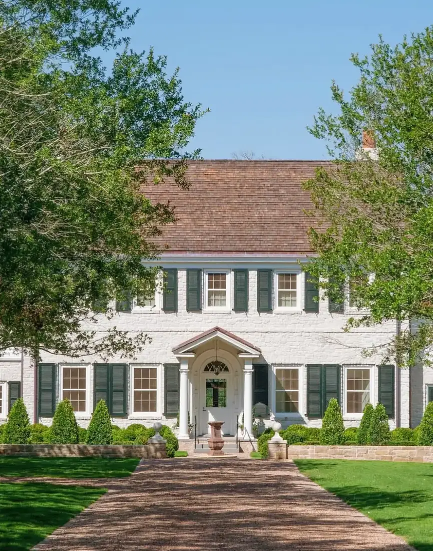 Whitewashed brick colonial house with dark green shutters and a symmetrical front