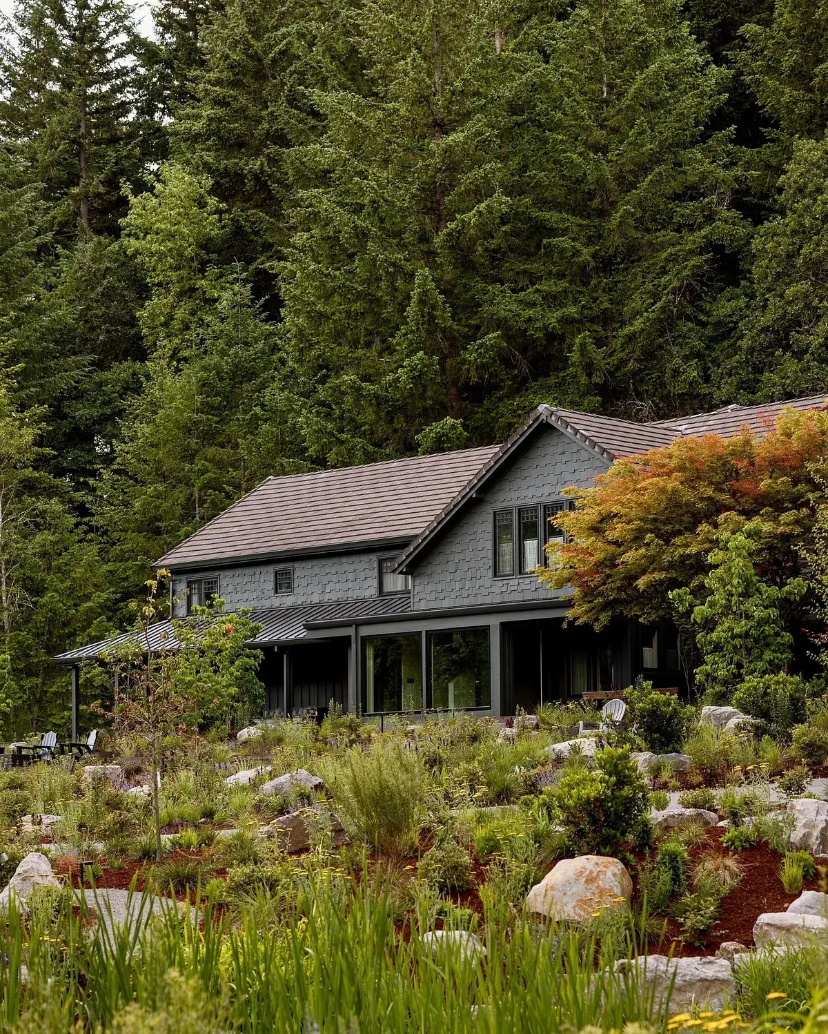 Dark timber cabin in a forest clearing edged by a wildflower meadow