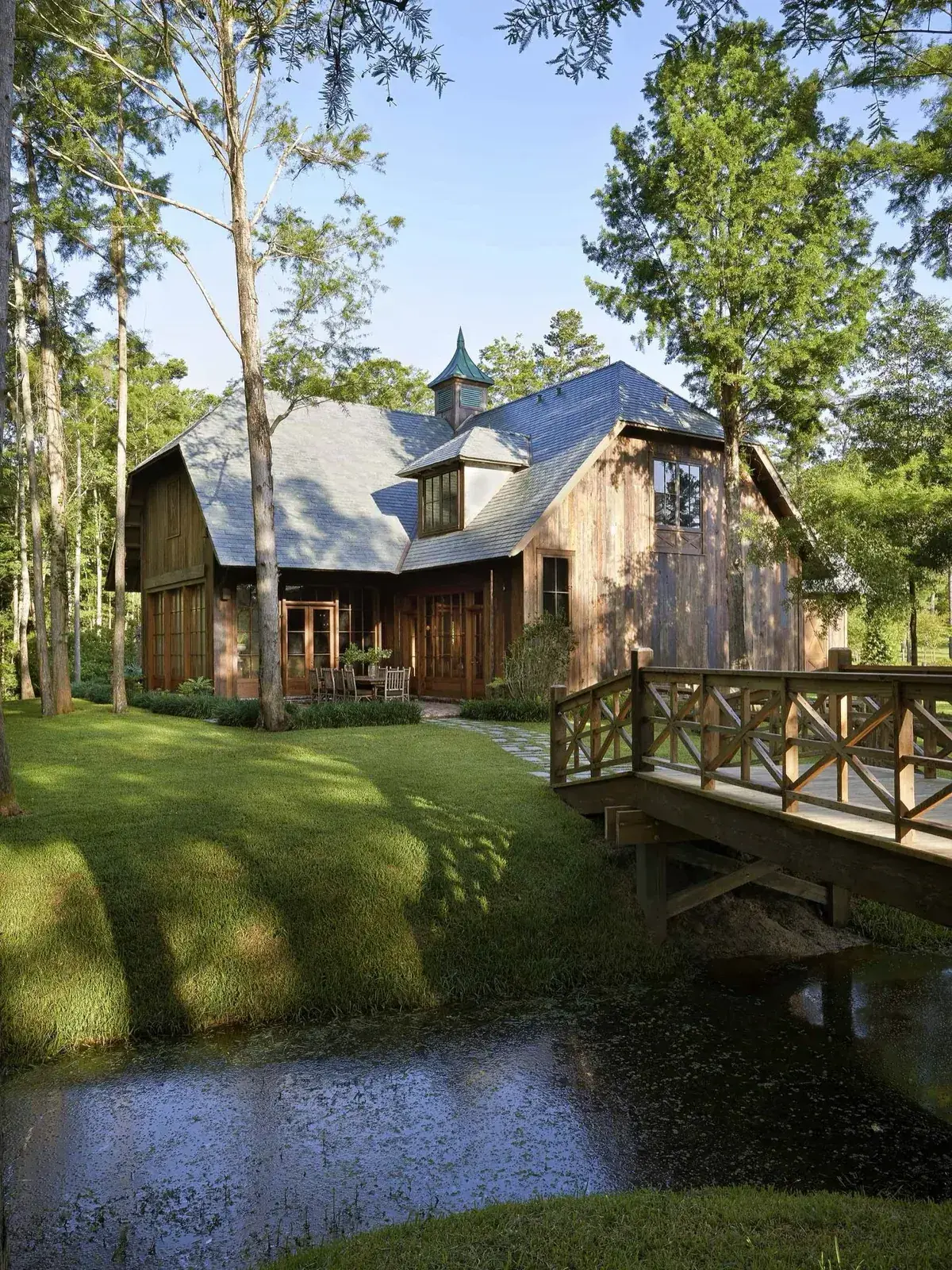 Weathered timber barn house reached by a wooden footbridge