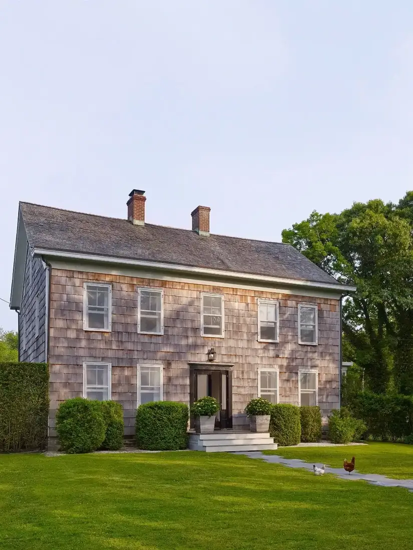 Colonial saltbox clad in cedar shingles weathering unevenly to silver and tan