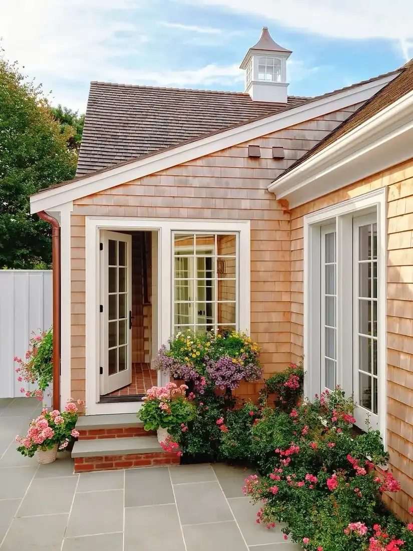 Cottage in cedar shingles with white cupola and rose beds