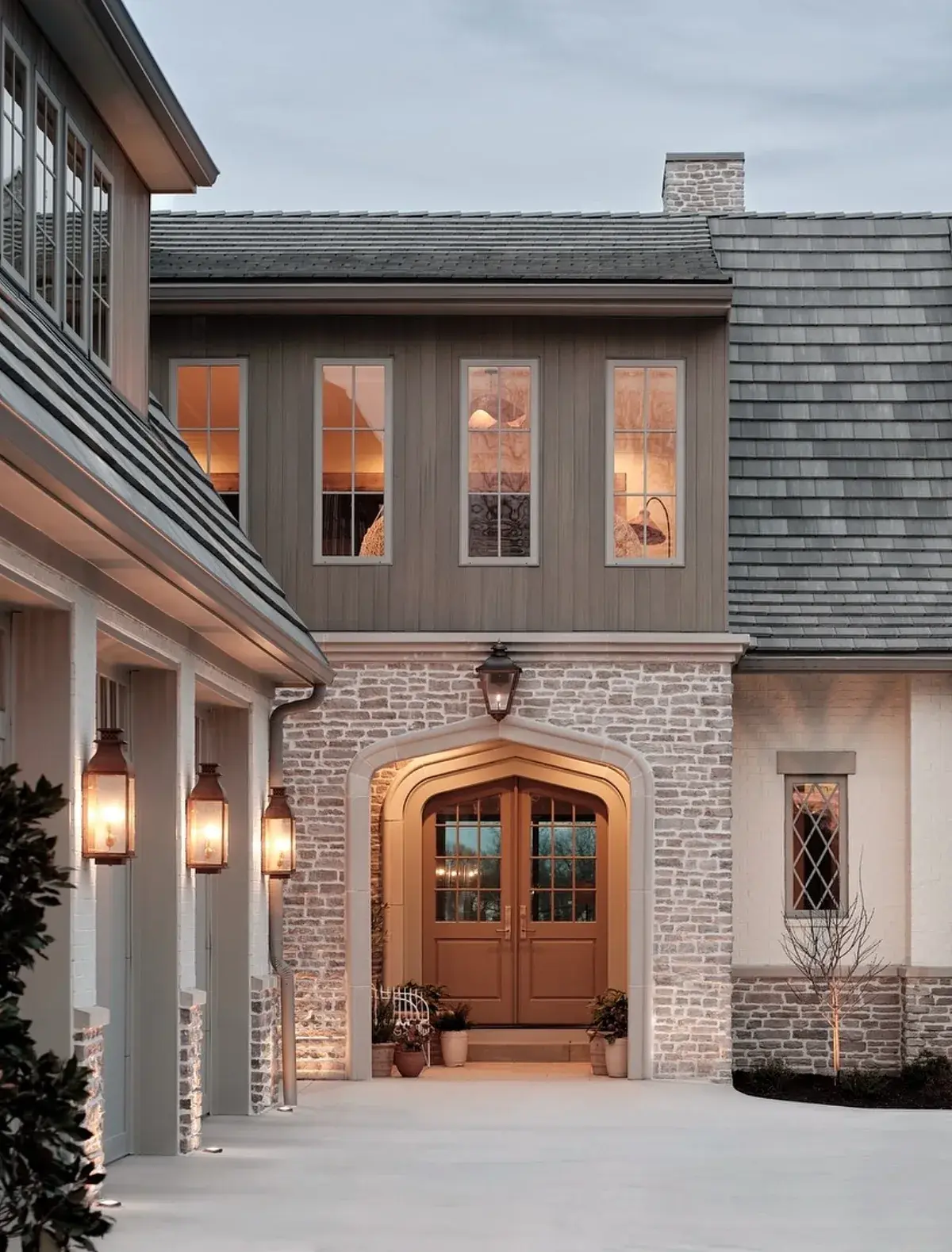 Stone and shingle house with an arched timber front door