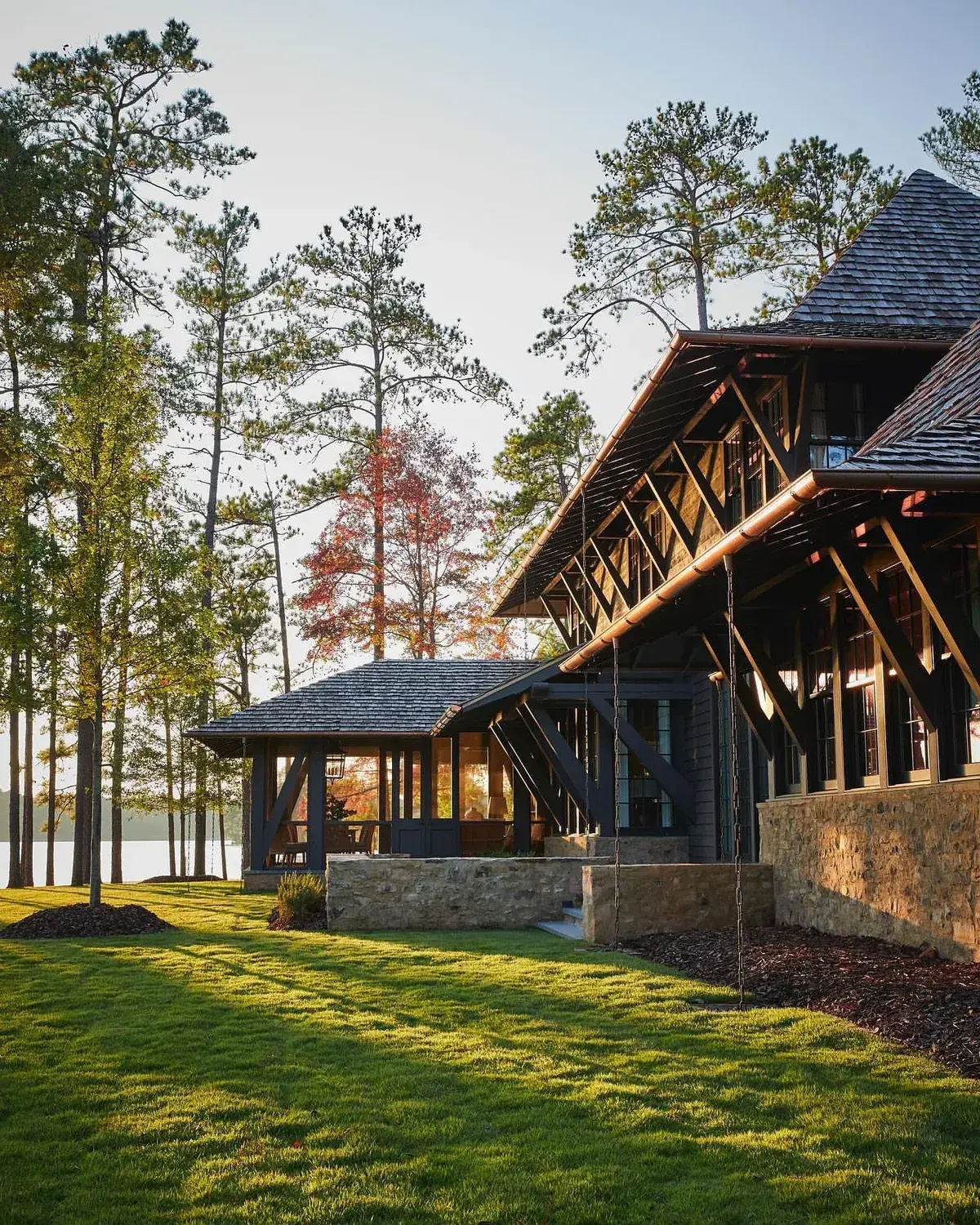 Timber frame lake house with a shingle pavilion beside it