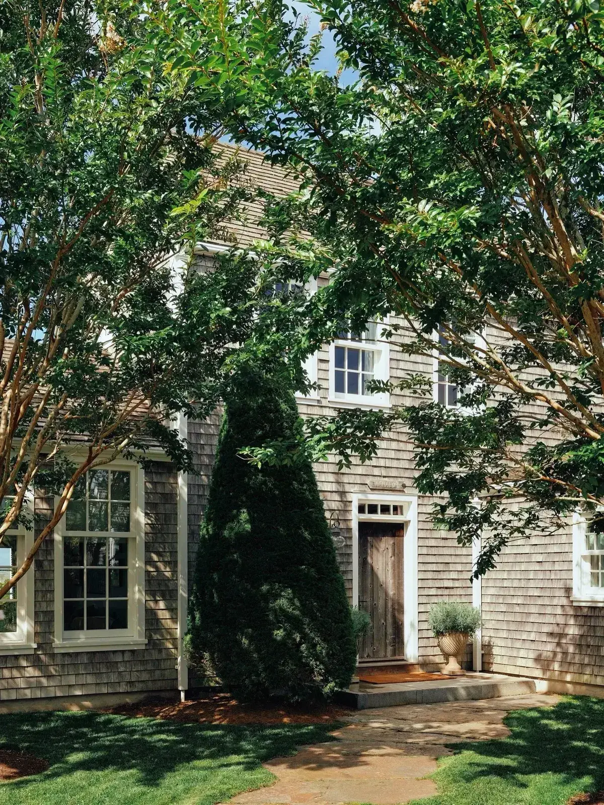 Weathered shingle cottage with crepe myrtle in bloom beside it