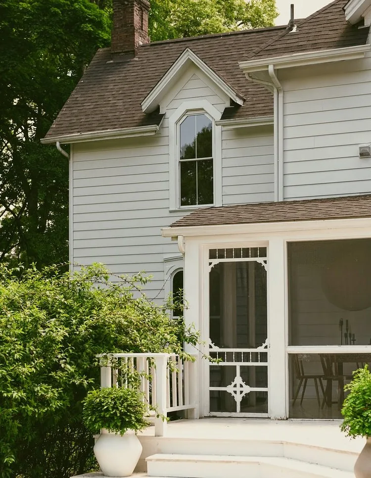 White clapboard screened porch set under a shingle gable