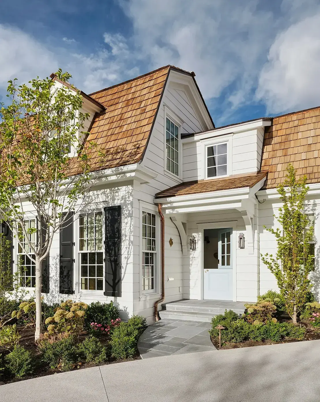 White cottage with a cedar shake gable and a dormer window