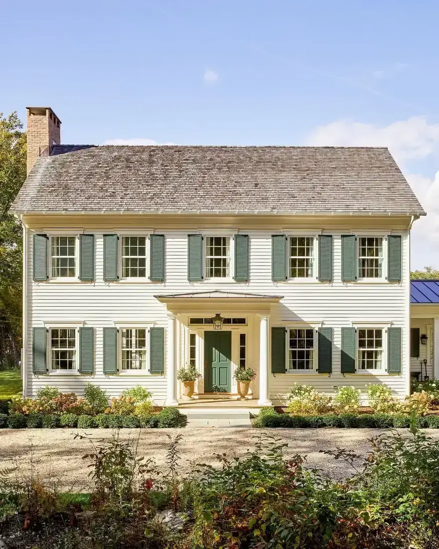 Cream colonial house with sage green shutters, shutter dogs and a small pedimented portico