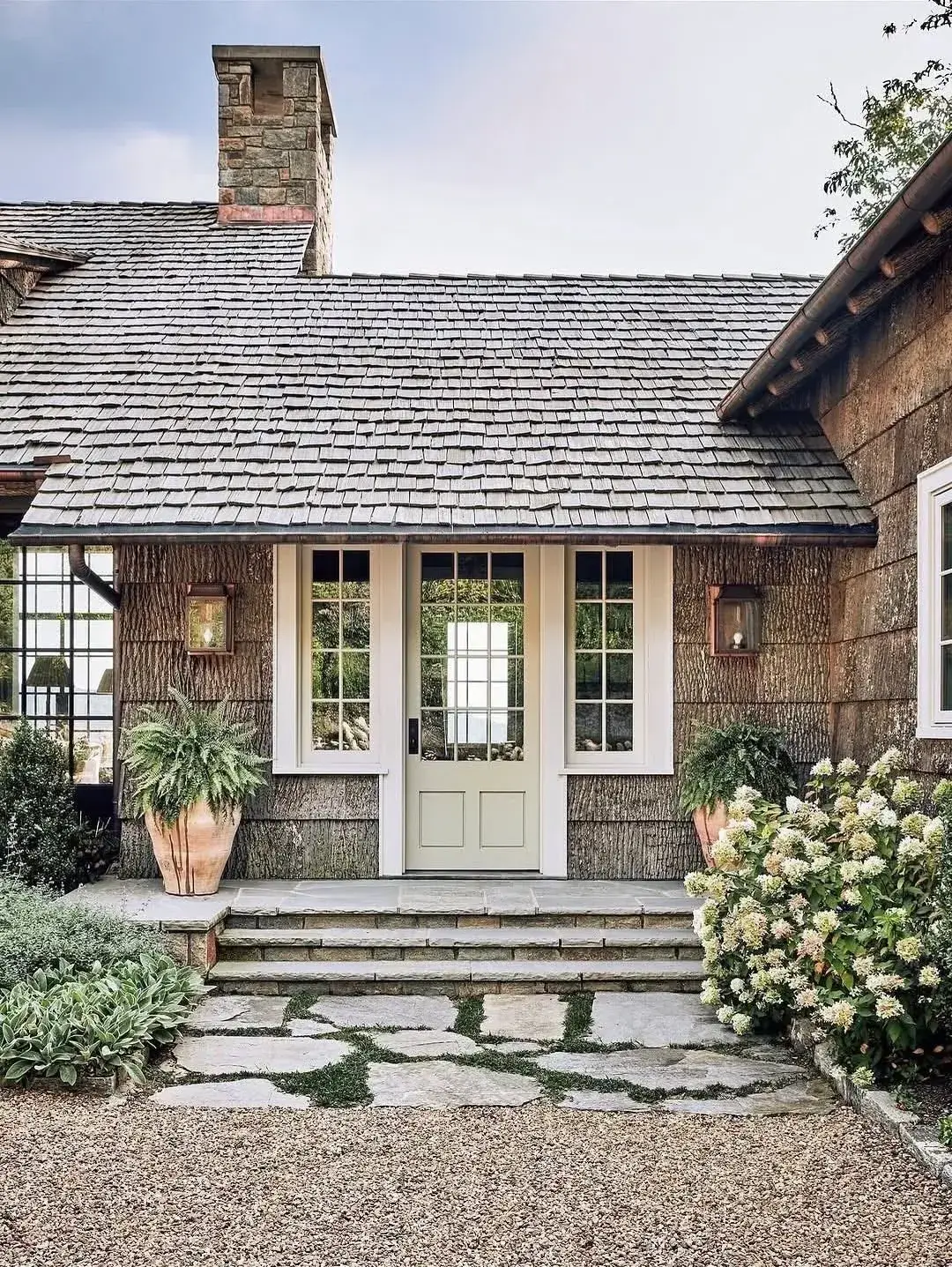 Bark sided cottage with cream glazed door, sidelights, copper lanterns and stone steps