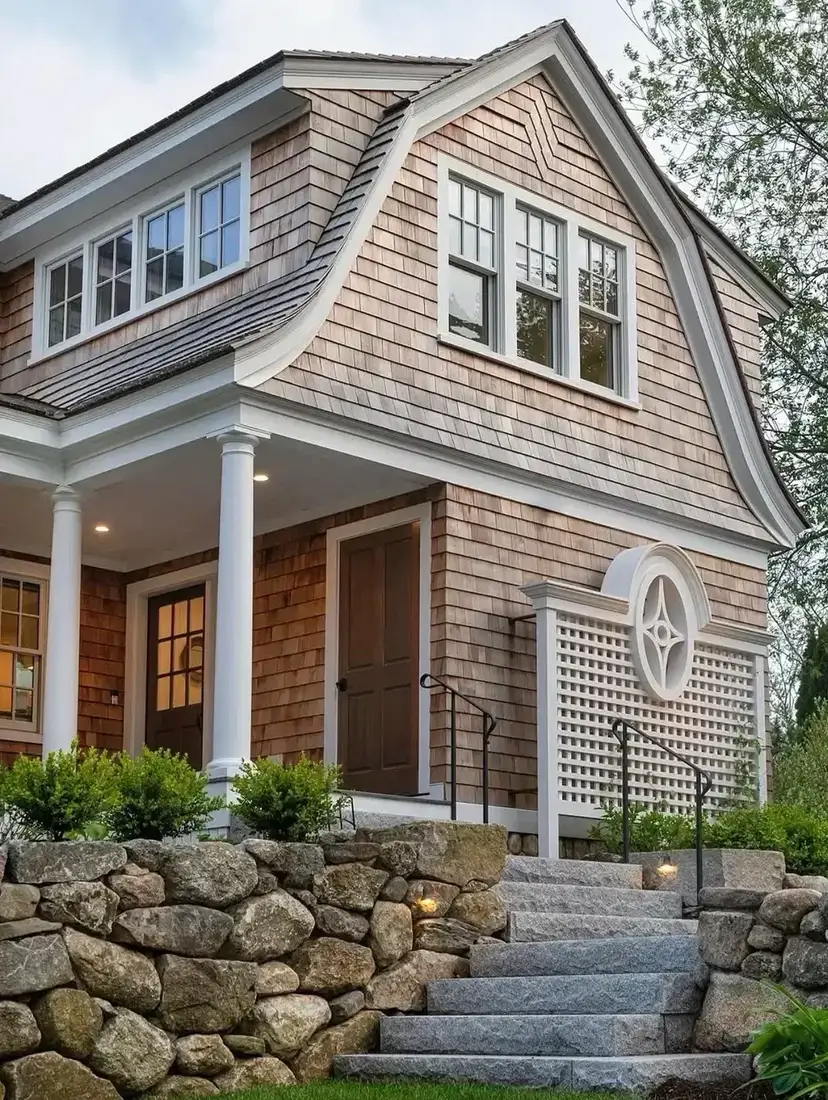 Natural cedar gambrel with white trim and columns above a fieldstone retaining wall