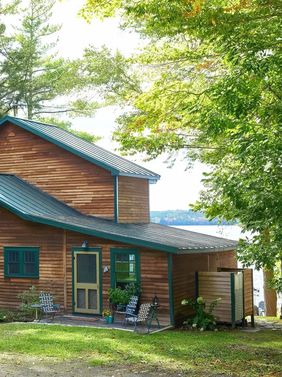 Cedar cottage with green trim sitting close to the lake edge