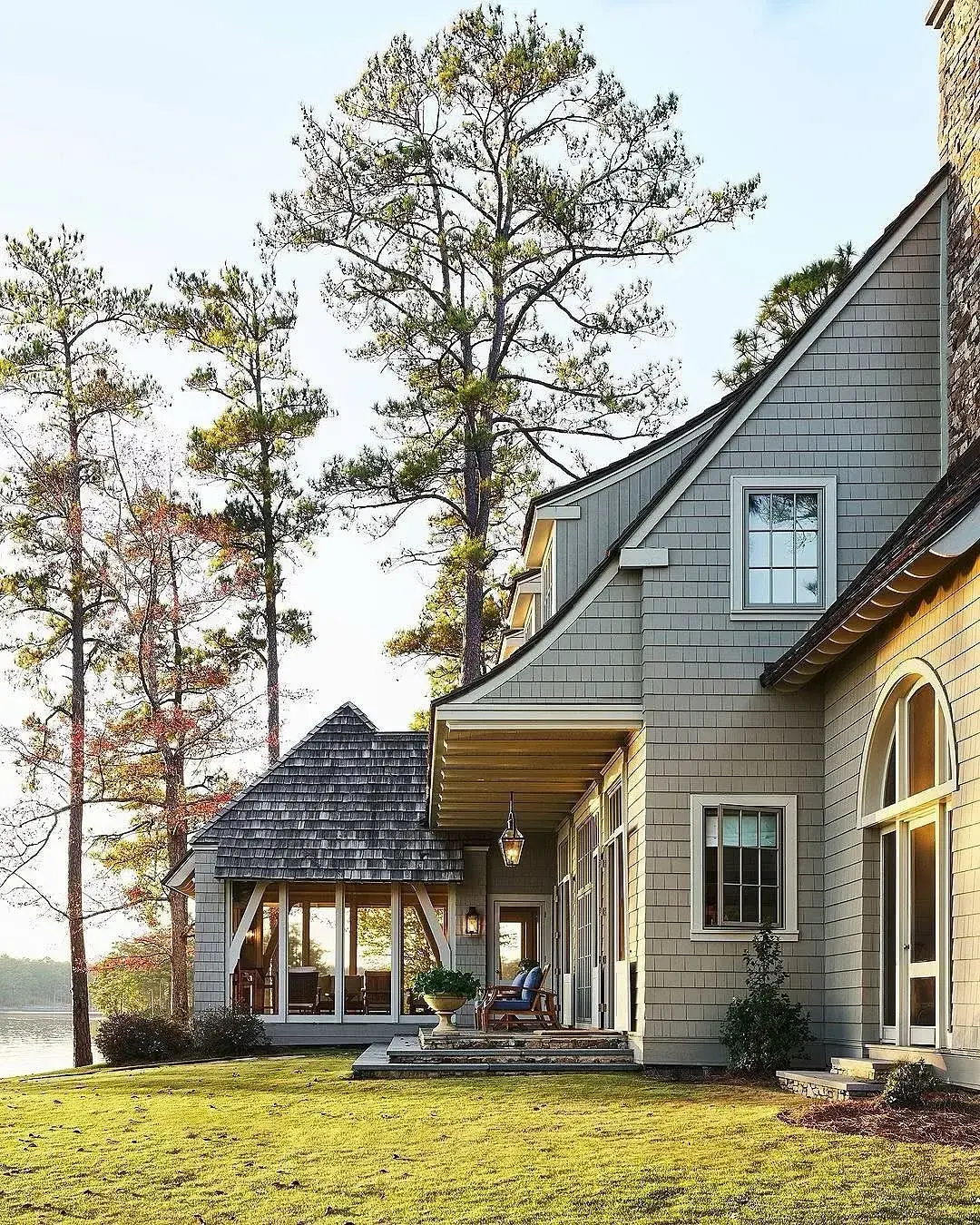 Grey lake house exterior with a backyard sloping down to the water