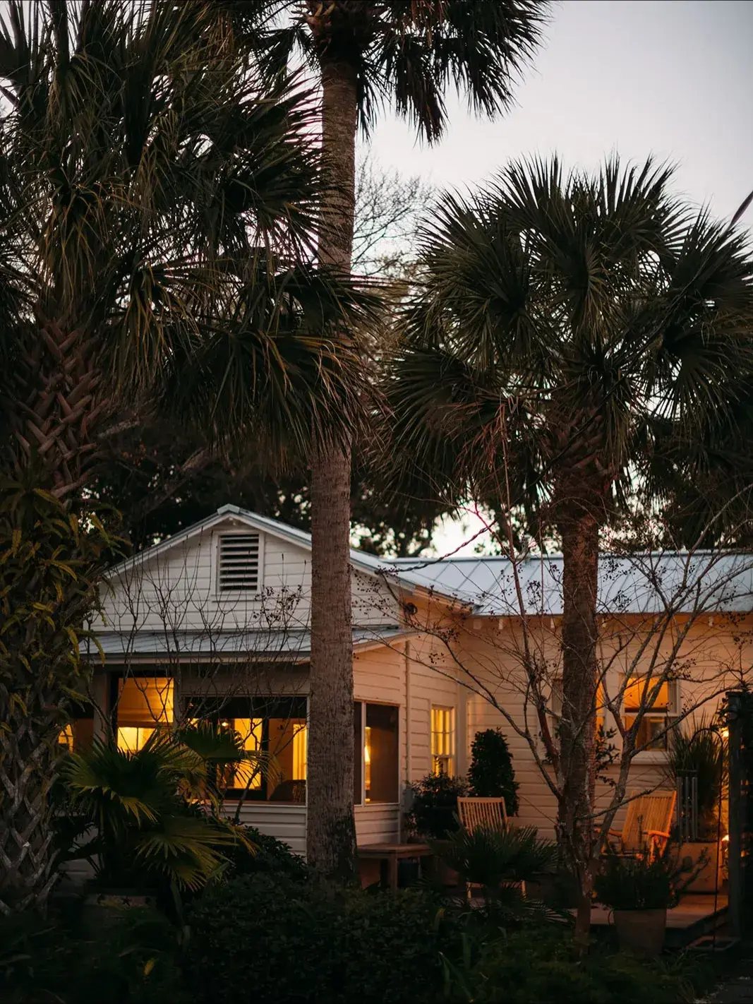 White cottage with palm trees glowing in warm evening light