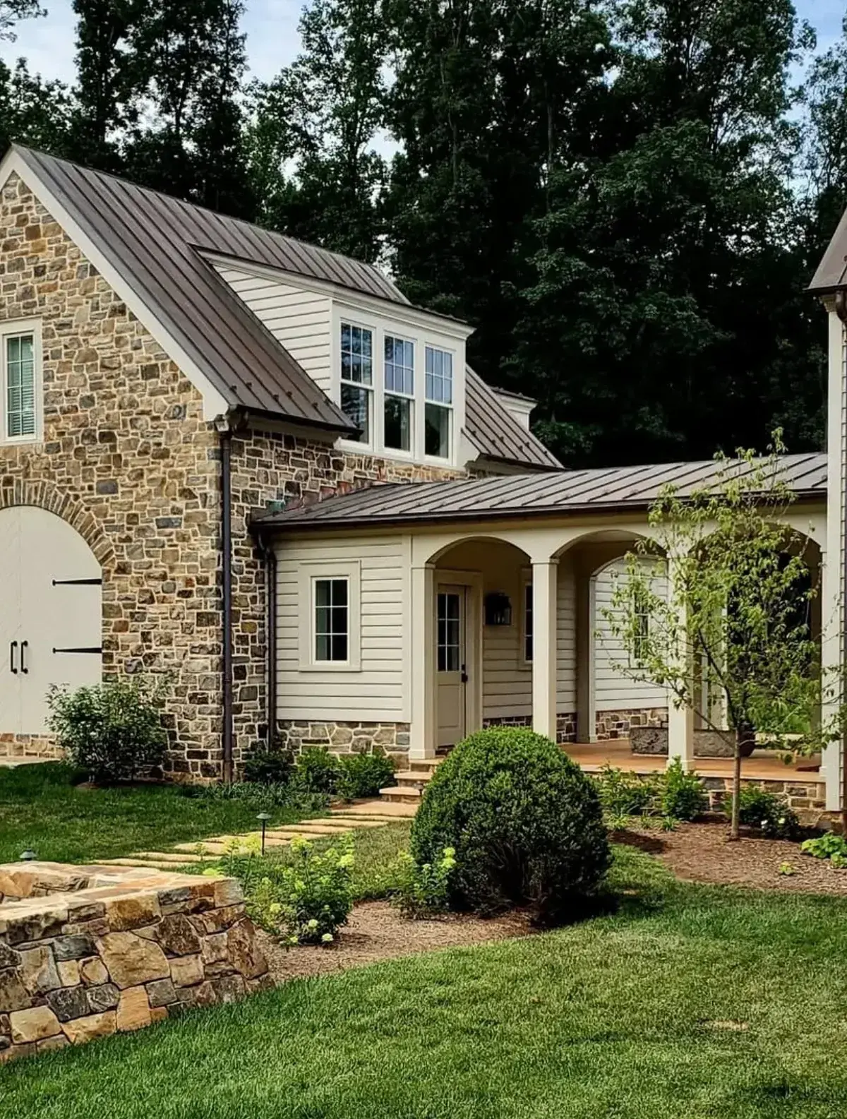 Stone cottage with a bronze standing seam roof on a linked walkway and dormer